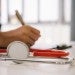 Person taking notes by a stethoscope